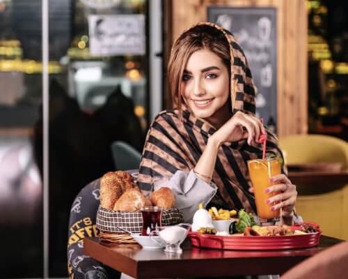 A woman smiling while she eats at a local restaurant.